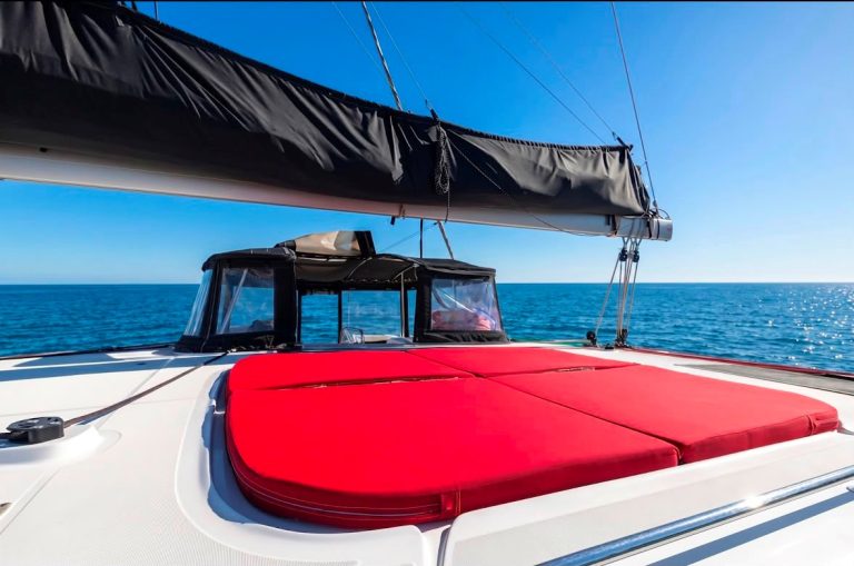 Red sunbed cushions on the Lagoon 45 catamaran with the open sea – Espreguiçadeiras vermelhas no catamarã Lagoon 45 com o mar ao fundo