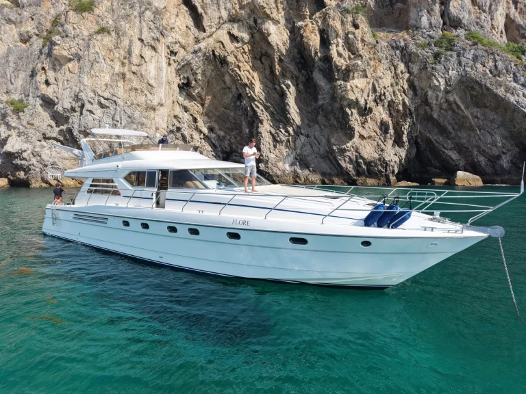 Princess 65 yacht at anchor next to the cliffs with guests on the flybridge – Iate Princess 65 ancorado junto às falésias com convidados no flybridge